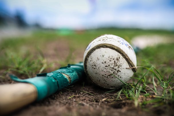 A hurley and sliotar in the grass with an out of focus background
