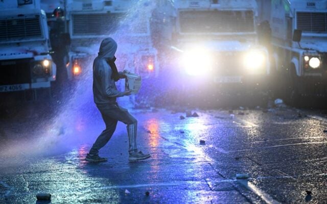 June 11, 2025:  A member of the crowd throws an object towards the PSNI riot squad officers as they form a blockade near Harryville bridge to stop potential rioters from accessing the Clonavon terrace area in Ballymena, Co Antrim.
