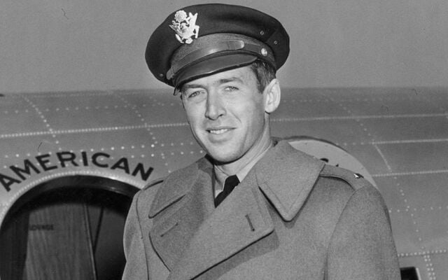 Portrait of American actor Jimmy Stewart (1908 - 1997) in his Air Force cap and wool overcoat, in front of a military airplane circa 1942.