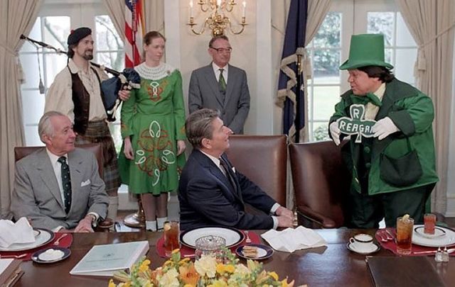March 17, 1986: President Reagan and Don Regan celebrating St. Patrick\'s Day with a Leprechaun and Irish Dancer during an Issues Briefing Luncheon in the cabinet room.