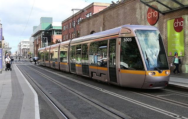 The LUAS tram driving by the CHQ building in Dublin 1.
