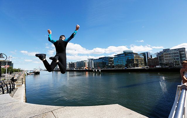 Pictured are young crowds of people jumping into the water while enjoying the sunny weather in Liffey River at The Docklands Area in Dublin.