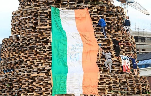 Children climb a bonfire in Sandy Row south Belfast. The flag contains the letters "KAT" for "Kill All Taigs," meaning Irish nationalists, and "ATAT," meaning "All Taigs Are Targets."