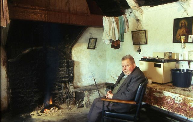 Tommy Cullen sits in front of his hearth in the family's traditional thatched cottage.