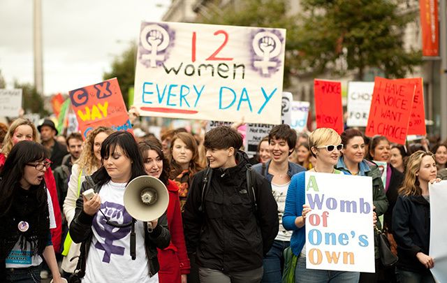 Group of women holding informational posters regarding abortion.