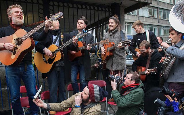 Glen Hansard (far left) and other musicians perform outside of Apollo House last month.