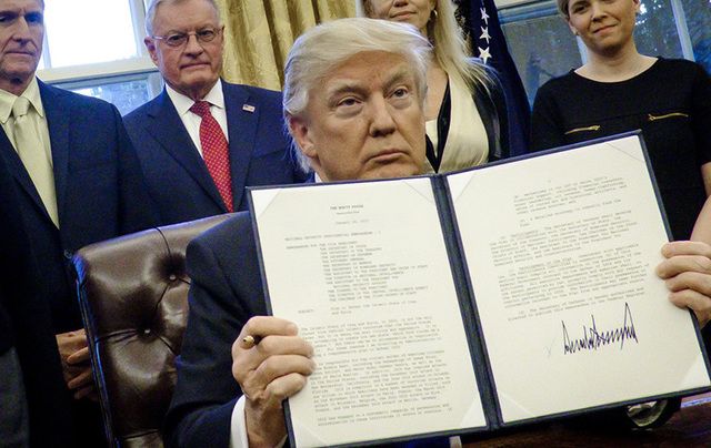 President Trump holds one of his executive orders in the Oval Office.