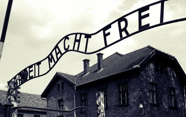 A sign reading \"Arbeit macht frei\" (\"Work sets you free\") hanging above the entrance to Auschwitz.