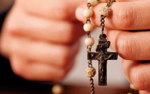 Hands holding rosary beads. 