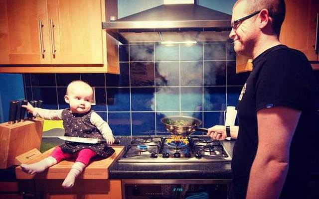 Photoshopped photo shows baby holding a knife near the stove as her dad looks on.
