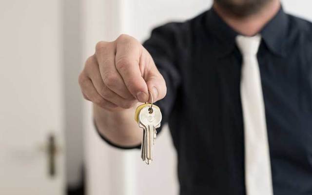 A man holds out a set of keys.