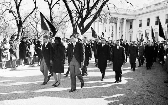 Photograph of Jacqueline Kennedy, accompanied by her brothers-in-law, Attorney General Robert F. Kennedy and Senator Edward Kennedy, walking from the White House as part of the funeral procession accompanying President Kennedy\'s casket to St. Matthew\'s Cathedral.