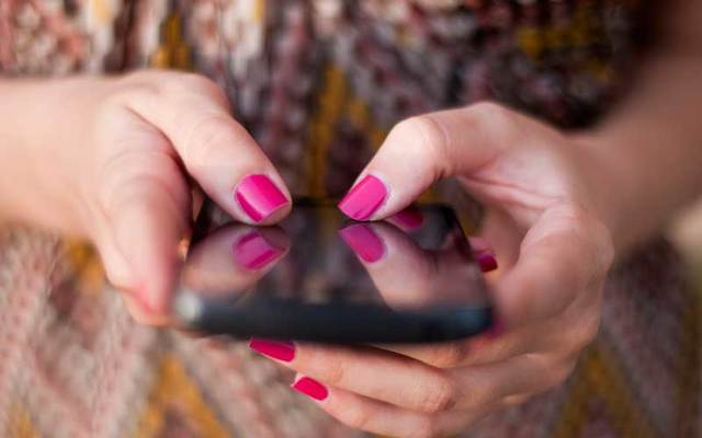 A woman\'s hands holding a smart phone.