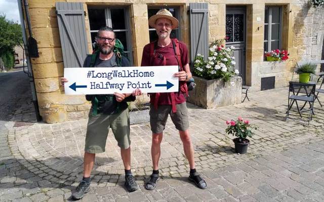 Eamonn Donnelly (left) and Sepp Tieber hold up a sign saying #LongWalkHome Halfway Point.