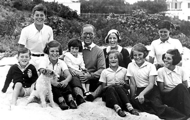 September 4, 1931: The Kennedy Family at Hyannis Port. L-R: Robert Kennedy, John F. Kennedy, Eunice Kennedy, Jean Kennedy (on lap of) Joseph P. Kennedy Sr., Rose Fitzgerald Kennedy (who was pregnant with Edward \"Ted\" Kennedy at time of this photo), Patricia Kennedy, Kathleen Kennedy, Joseph P. Kennedy Jr. (behind) Rosemary Kennedy. The dog in the foreground is Buddy.