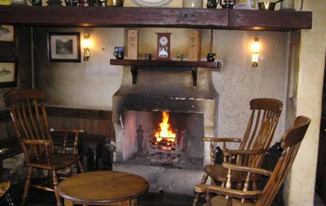 A cosy fireplace with some turf on the fire. 