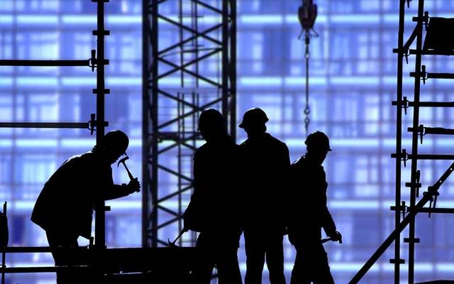 Construction workers in silhouette.