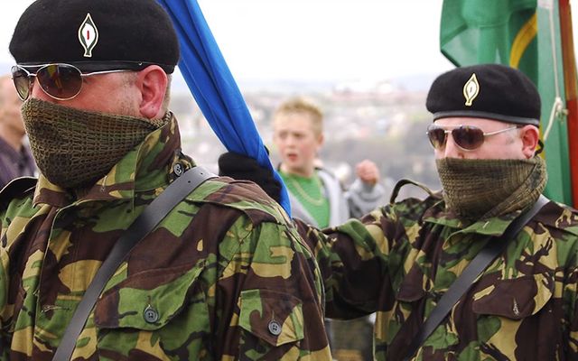 Irish Republican Army members march, wearing a lily in their hates to remember fallen combatants.