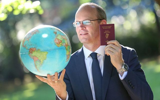 Minister for Foreign Affairs and Deputy Leader Simon Coveney poses with an Irish passport and a globe.