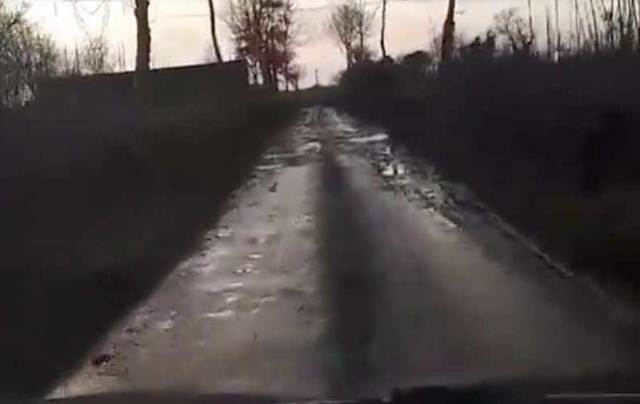 Horrible Irish road filled with potholes and water.