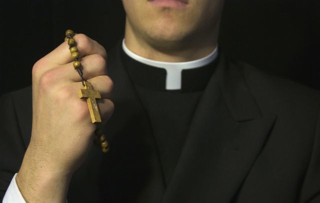 A Catholic priest holding rosary beads.