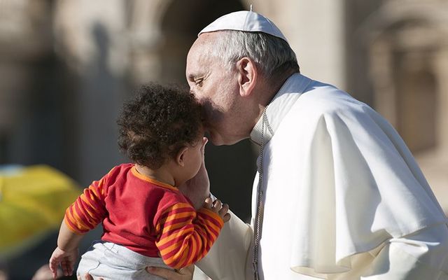 Pope Francis kissing a baby during a public visit.