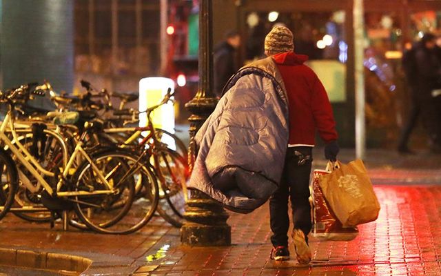 A homeless man walking in the rain, on the streets of Dublin.