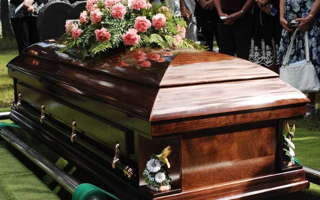 Mourners at a funeral gather around a casket.