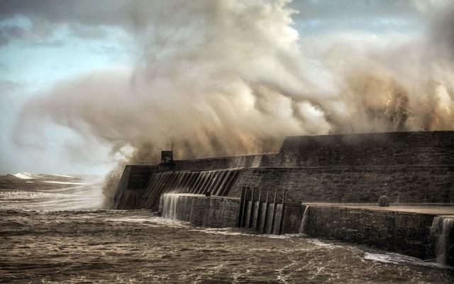 Porthcawl lighthouse and pier in the jaws of Storm Ophelia as the hurricane hits the coast of South Wales, UK.\n