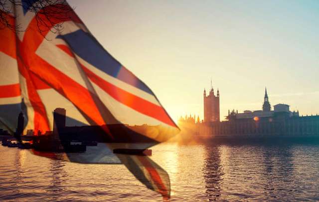 British union jack flag and Big Ben Clock Tower and Parliament house at the city of Westminster in the background. 