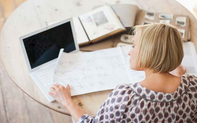 A woman at a table looking at a genealogical tree. 