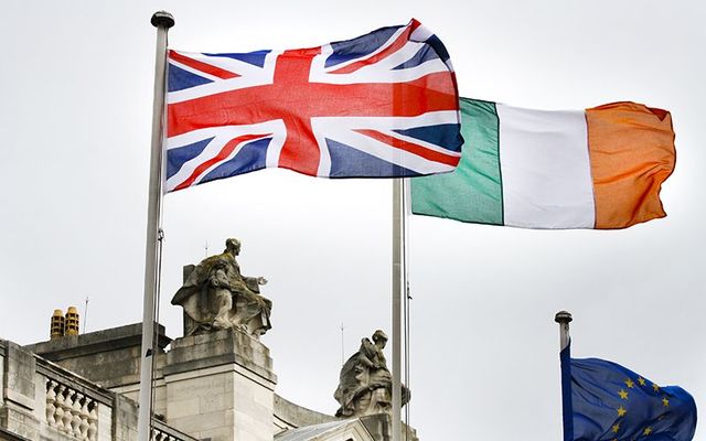 The Union Jack flag and the Irish tricolor flag flying above Stromont, Northern Ireland\'s government buildings.