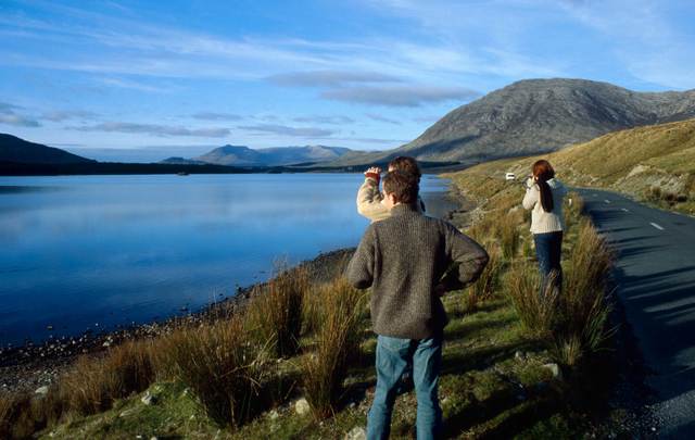A small group of people is standing on the roadside to gaze at the astonishing scenery of Connemara in Ireland.