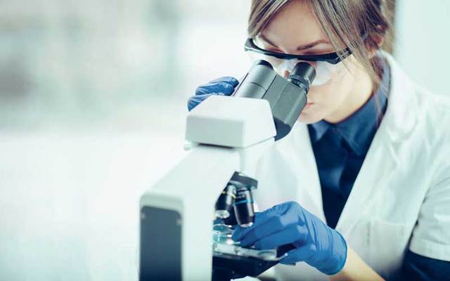 A scientist examines a sample under a microscope.