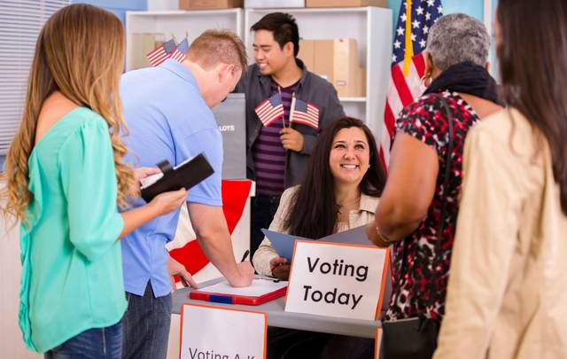 Multi-ethnic, mixed age group of people registering and voting in the November USA elections at their local polling station.