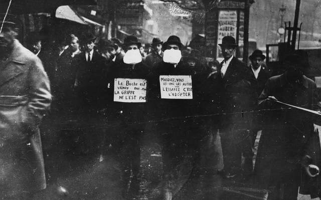  Two men wearing and advocating the use of flu masks in Paris during the Spanish flu epidemic which followed World War I. 