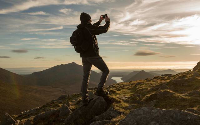 Hiker photographing Mourne Mountains, Northern Ireland.\n