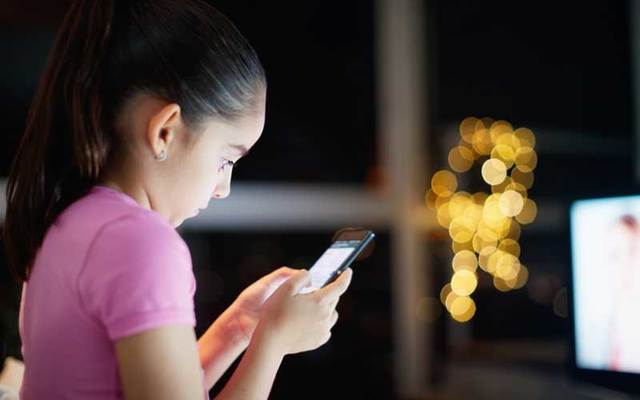 A young girl texts on a smartphone.