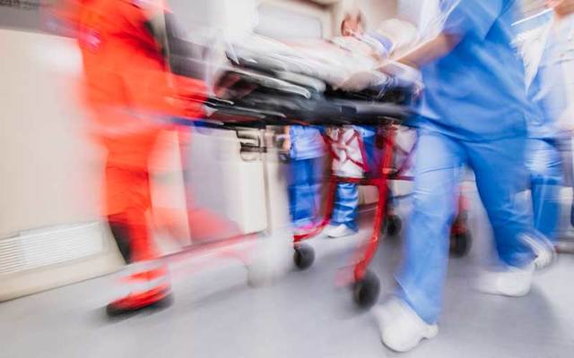Paramedics and nurses pull hospital trolley in an ER.