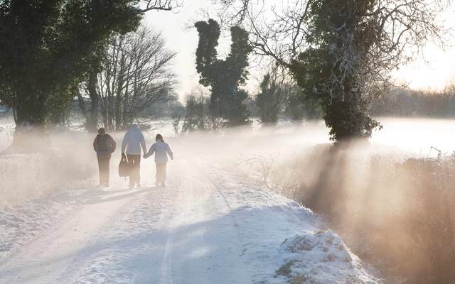 A mother bringing her two children to school on foot on a frosty winter morning. 