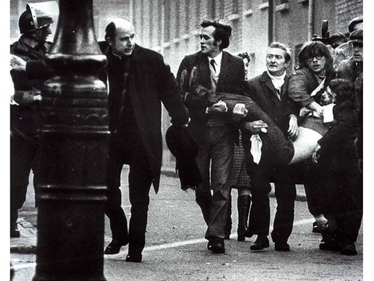 An iconic shot from Bloody Sunday of a wounded man being carried from the street by civil rights marchers.