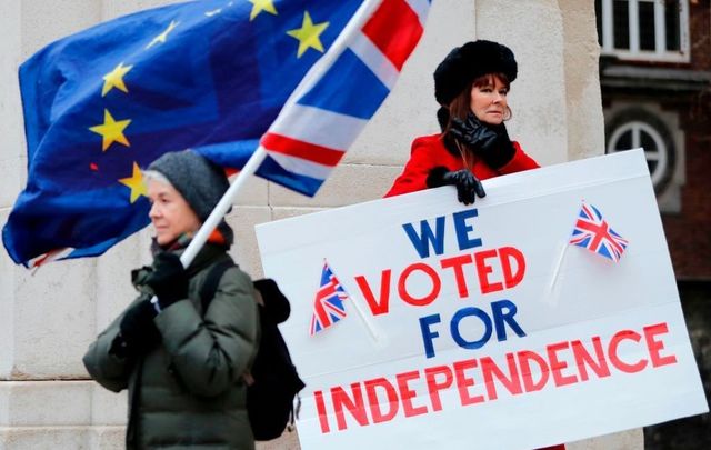 A pro-Brexit activist (R) holds a placard reading \'We Voted For Independence\' as an anti-Brexit campaigner waves a European Union and a Union flag. 
