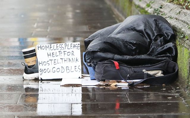 A beggar sits next to an ATM in Dublin.