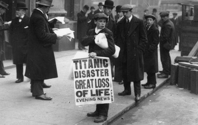 A newspaper seller in New York holds a sigh \"Titanic disaster - great loss of life\".