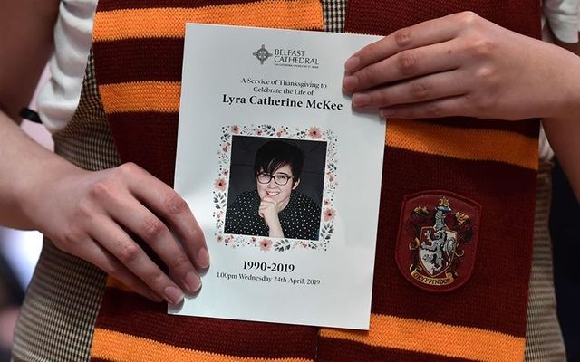 The funeral Mass leaflet for Lyra McKee held by a mourner wearing a Hufflepuff, Harry Potter scarf.