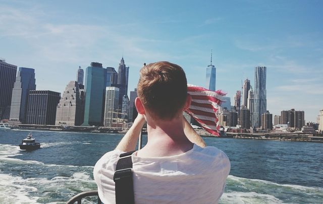 Rear view of man on ferry boat against city.