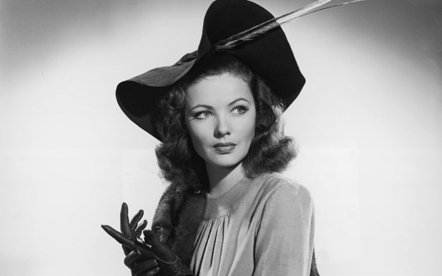 Studio portrait of American actor Gene Tierney (1920 - 1991) seated on a divan. She is wearing a hat with a feather, a mink stole, and leather gloves.