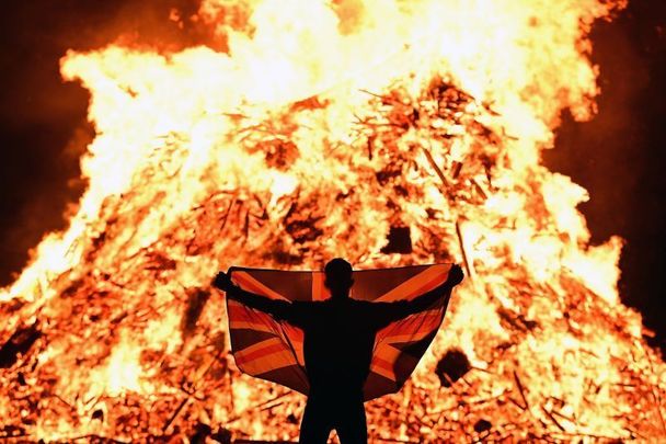July 11, 2021: A loyalist celebrates with a Union Jack flag as the 11th night bonfire, which marks the beginning of the annual Protestant 12th of July celebrations, is lit in Portadown, Northern Ireland. The 12th of July marches are a Protestant celebration of King William of Orange\'s victory over the Catholic King James at the Battle of the Boyne in 1690.