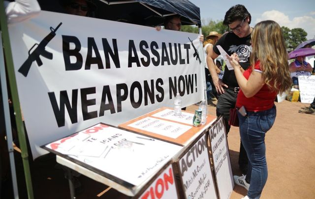 A \'Ban Assault Weapons Now\' sign is displayed near a voter registration table at a protest against President Trump\'s visit, following a mass shooting which left at least 22 people dead, on August 7, 2019, in El Paso, Texas.