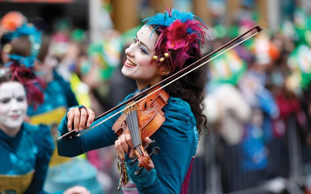 A performer during Dublin\'s St. Patrick\'s Day parade playing the fiddle.